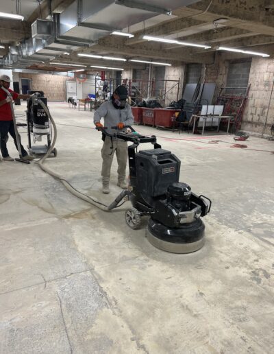 Man using a machine to smooth the floor, working diligently on the surface